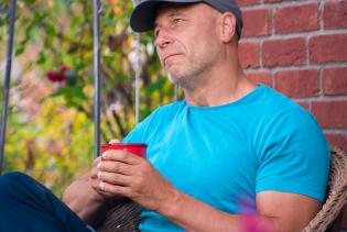 Thomas mit Tasse Kaffee in der Hand auf der Terrasse
