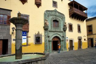 Gelb-/Ockerfarbenes Gebäude mit prunkvollem Eingangsportal aus schönen Stuckarbeiten