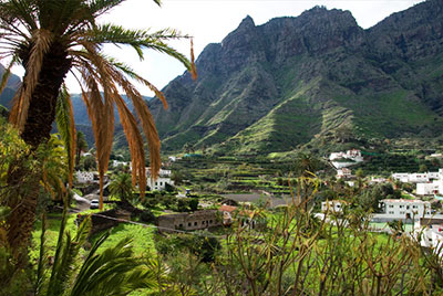 Panoramablick hinein in ein Tal mit hoch aufragenden grünen Bergwänden