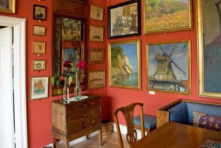 Zimmer der Villa: rote Wände mit vielen Gemälden bedeckt