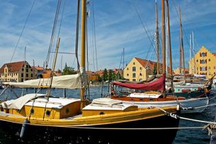 Schöne Holzyachten an der Pier vor dem Hintergrund von gelb leuchtenden Lagerhäusern