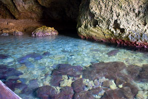 Die Farben des Wassers und der Felsen in einer Höhle schimmern blau bis lila