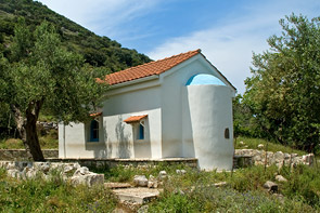 Weißgetünchte Kapelle mit Ziegeldach, davor ein Olivenbaum