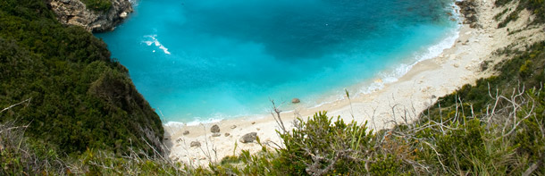 Strand mit türkisblauem Wasser von der Höhe einer Klippe aus fotografiert