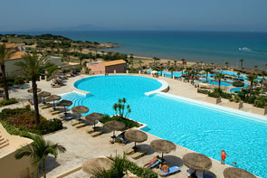 Blick über den türkisblauen Pool eines Hotels bis zum Meer